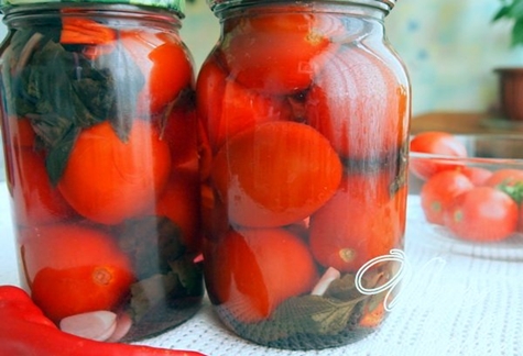 Tomates con vinagre de sidra de manzana sobre la mesa en frascos